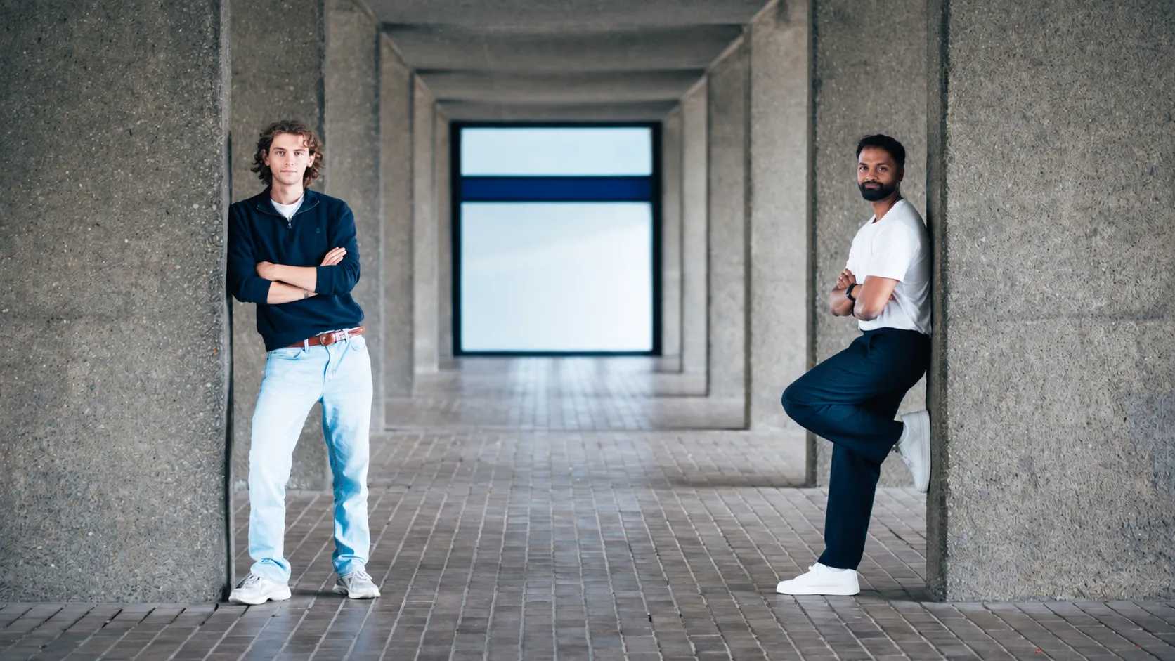Two men in a concrete corridor.png